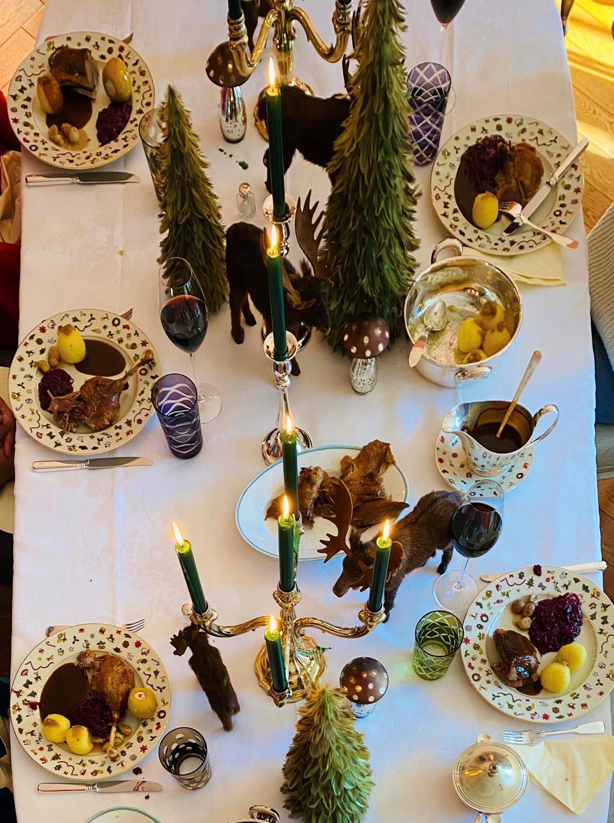 Festlich gedeckter Tisch mit weißer Tischdecke, auf Tellern angerichteter Gans mit Kartoffelklößen und Rotkohl – das Weihnachtsmenü vom Gänsetaxi des Club Astoria für zu Hause.